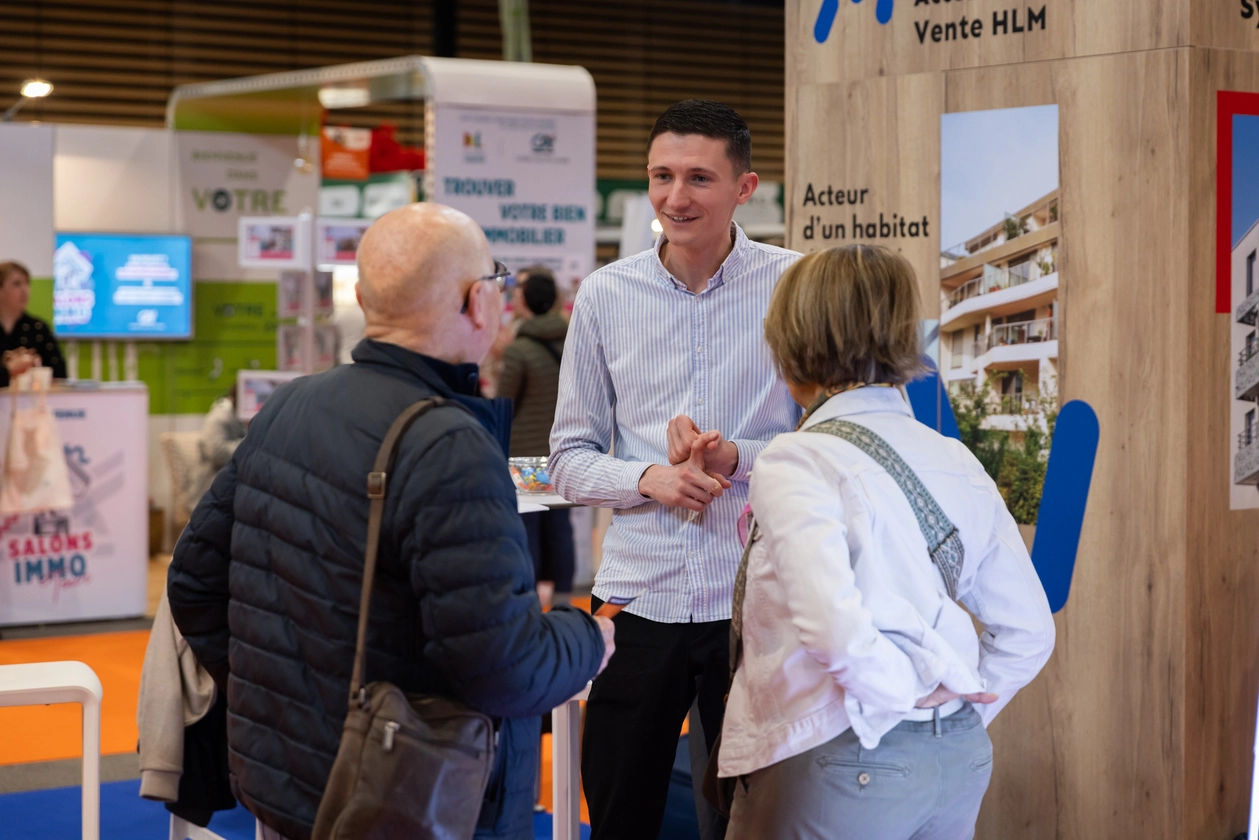 Un commercial parle à deux visiteurs sur un stand